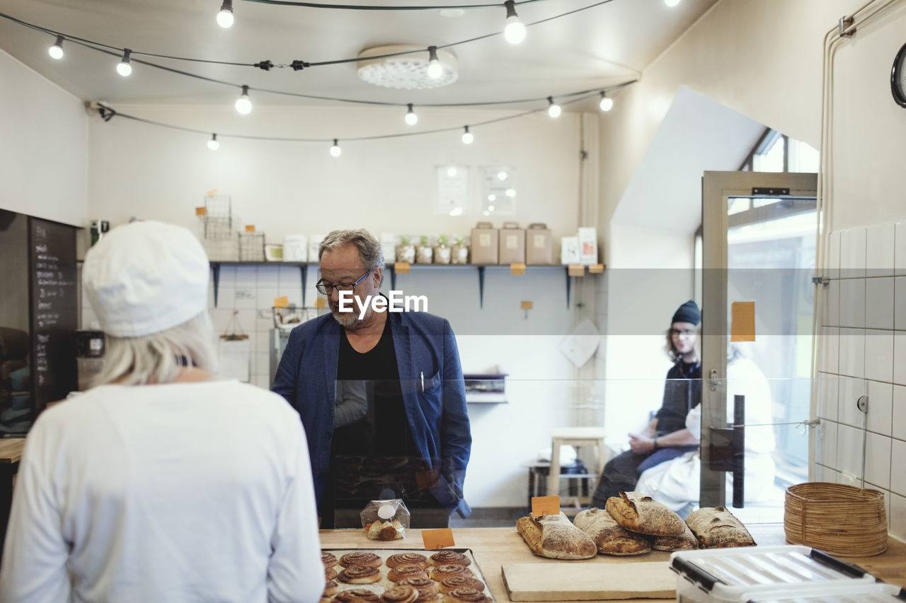 Male customer buying food from owner at bakery