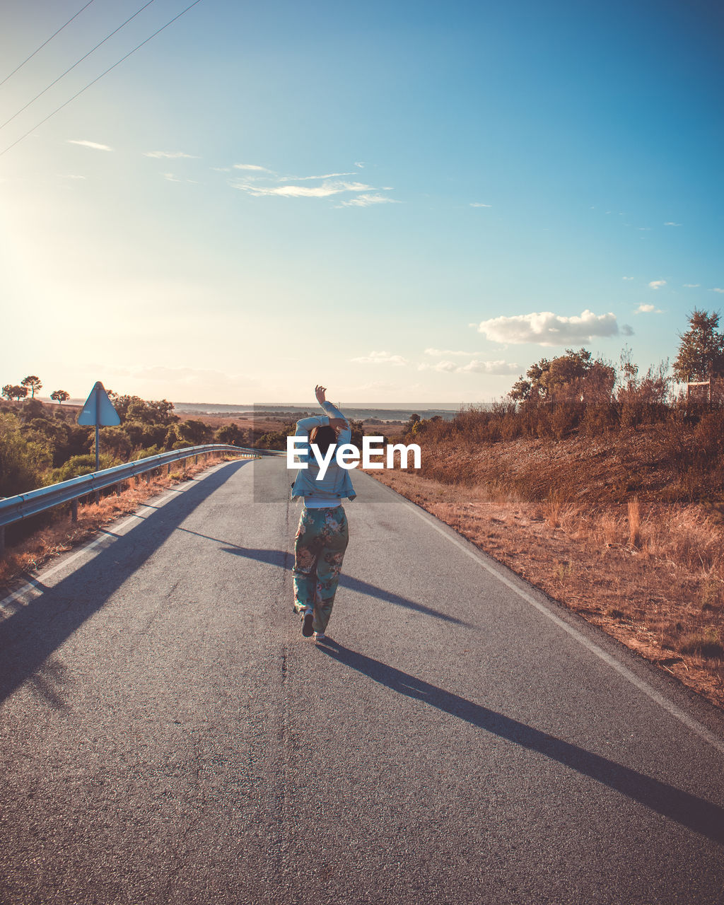 Rear view of woman walking on road against sky