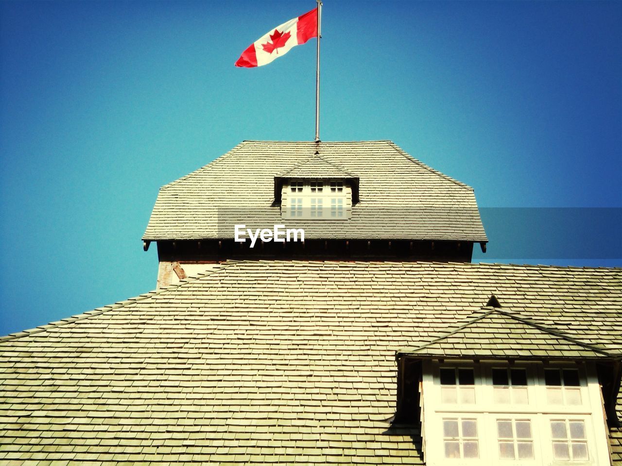 High section of house with canadian flag against clear blue sky