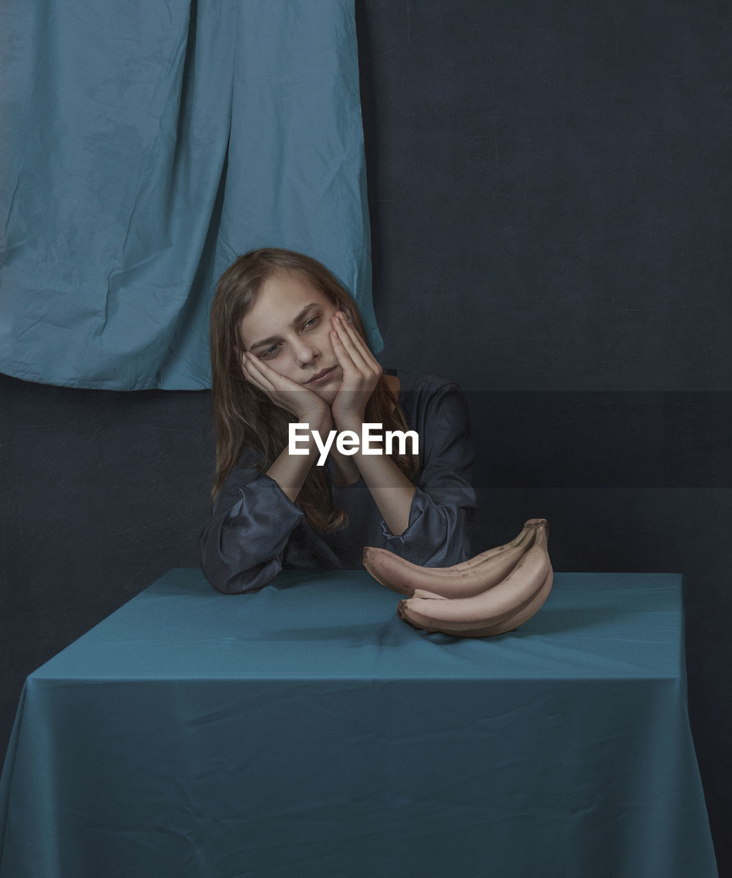 Portrait of a person sitting near the table  with white banana