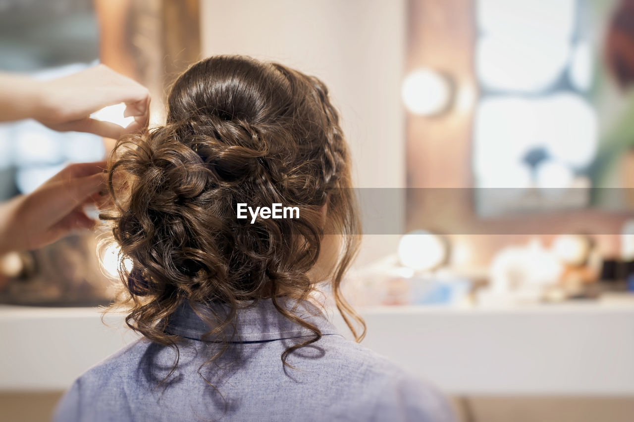 Hairdresser adjusting woman hair at home