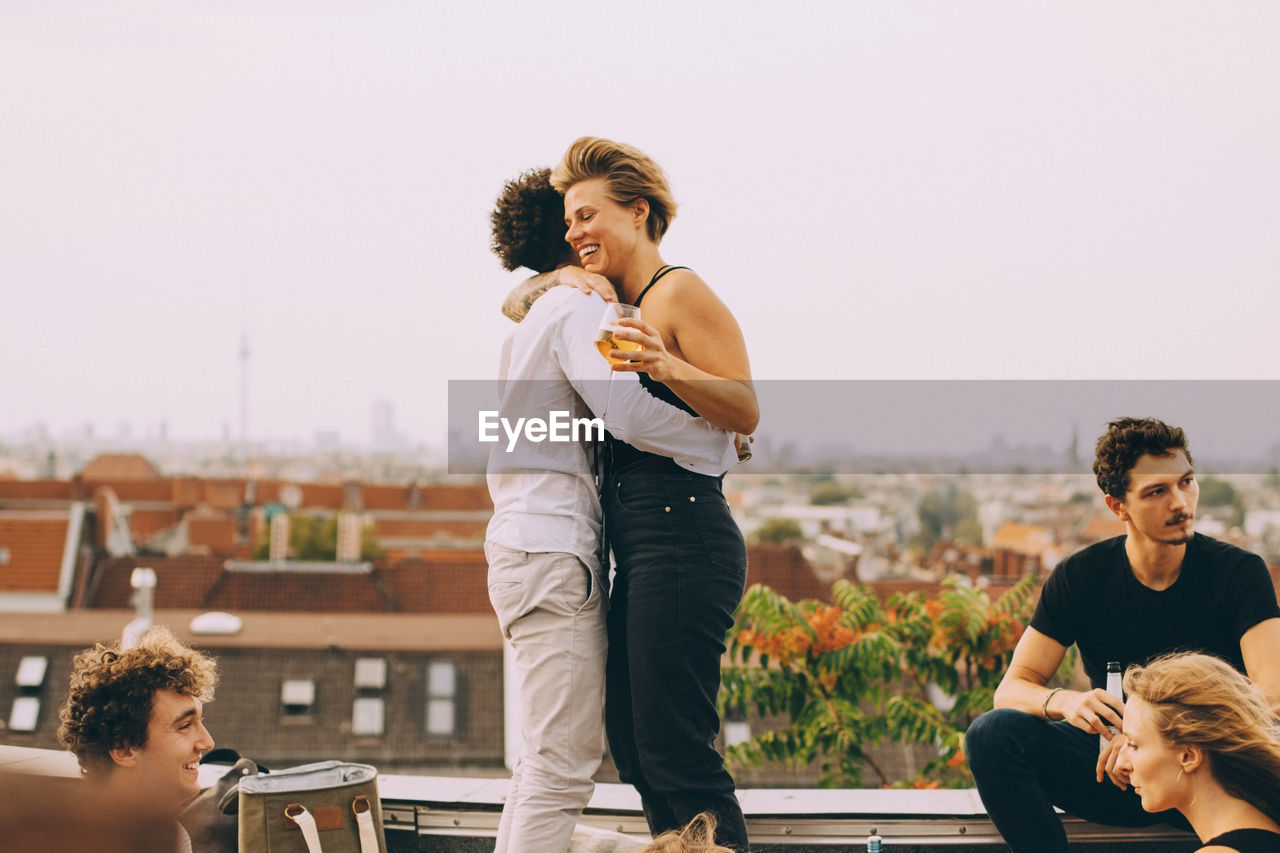 Man and woman embracing while enjoying party with friends at terrace