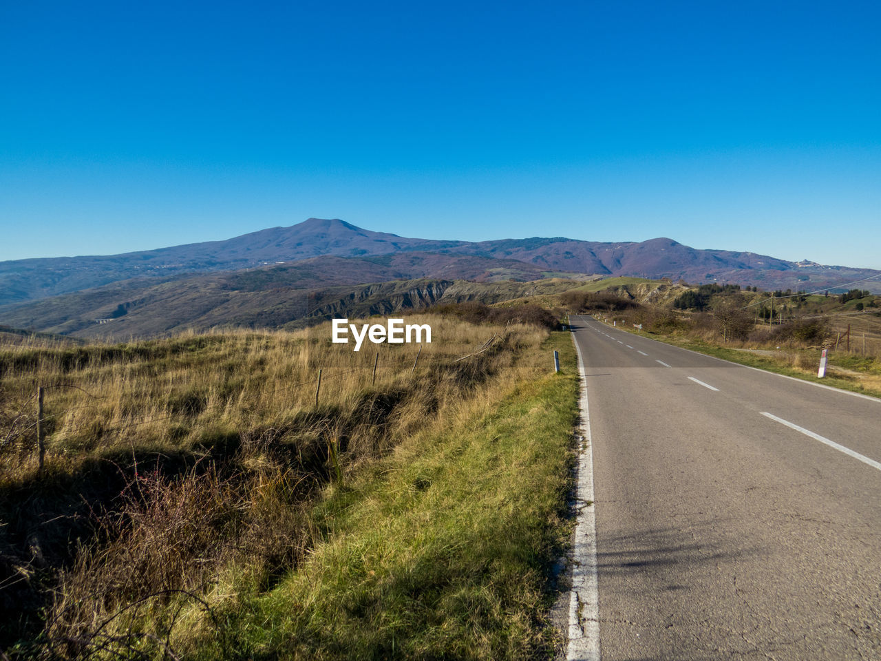 ROAD LEADING TOWARDS MOUNTAIN AGAINST BLUE SKY