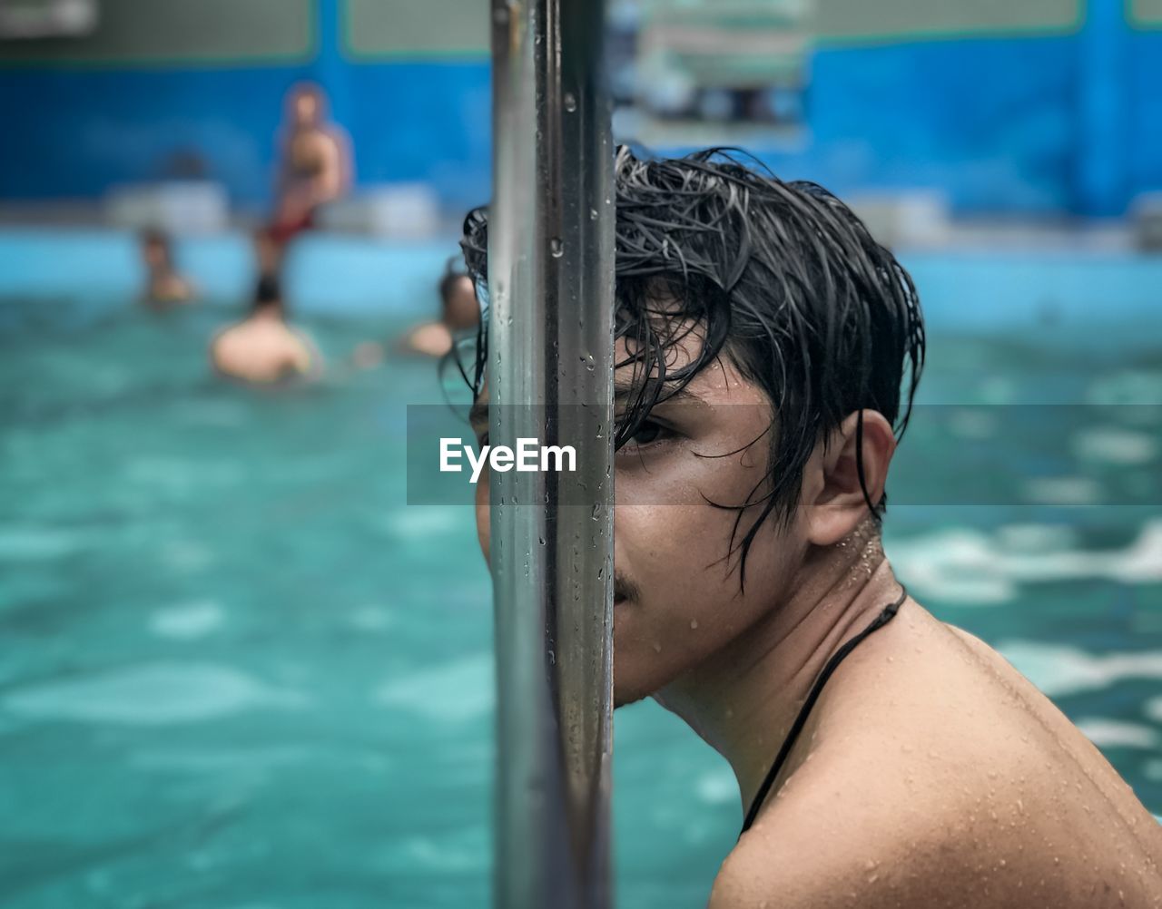 Portrait of shirtless man by swimming pool