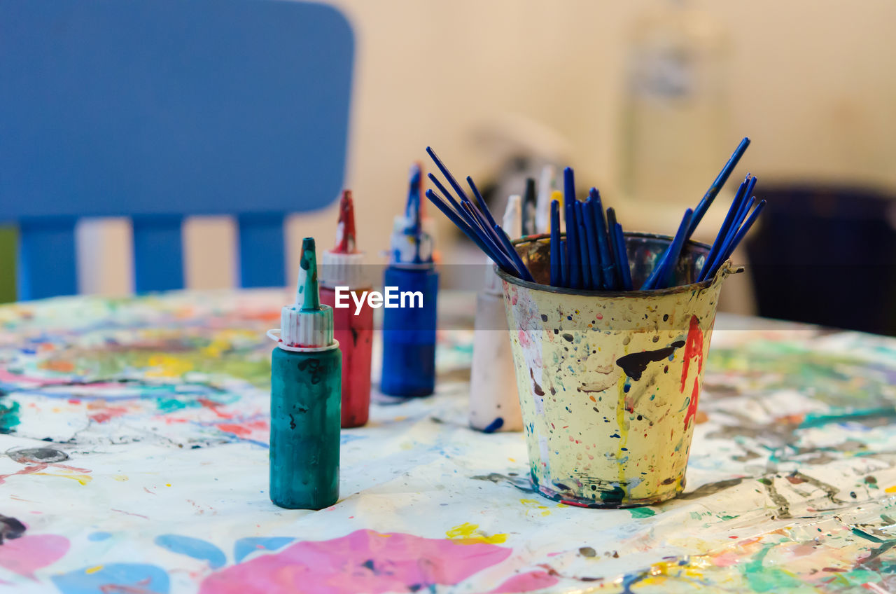 Paint brushes and water colors on messy table