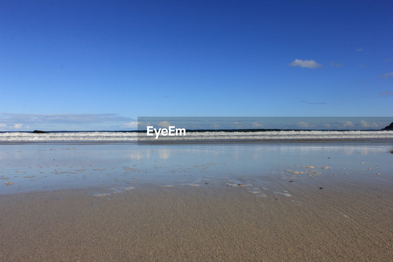 View of calm beach against blue sky