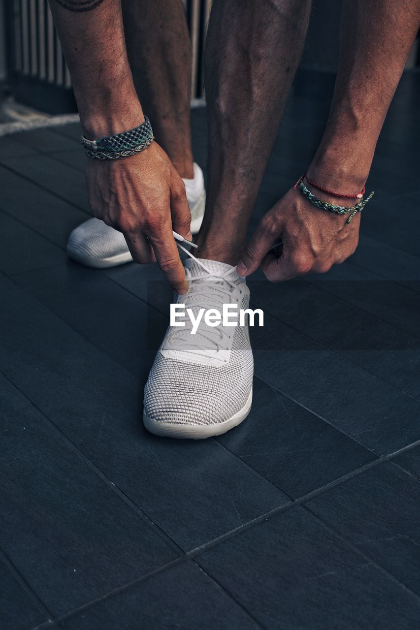 LOW SECTION OF MAN WEARING SHOES STANDING ON FLOOR