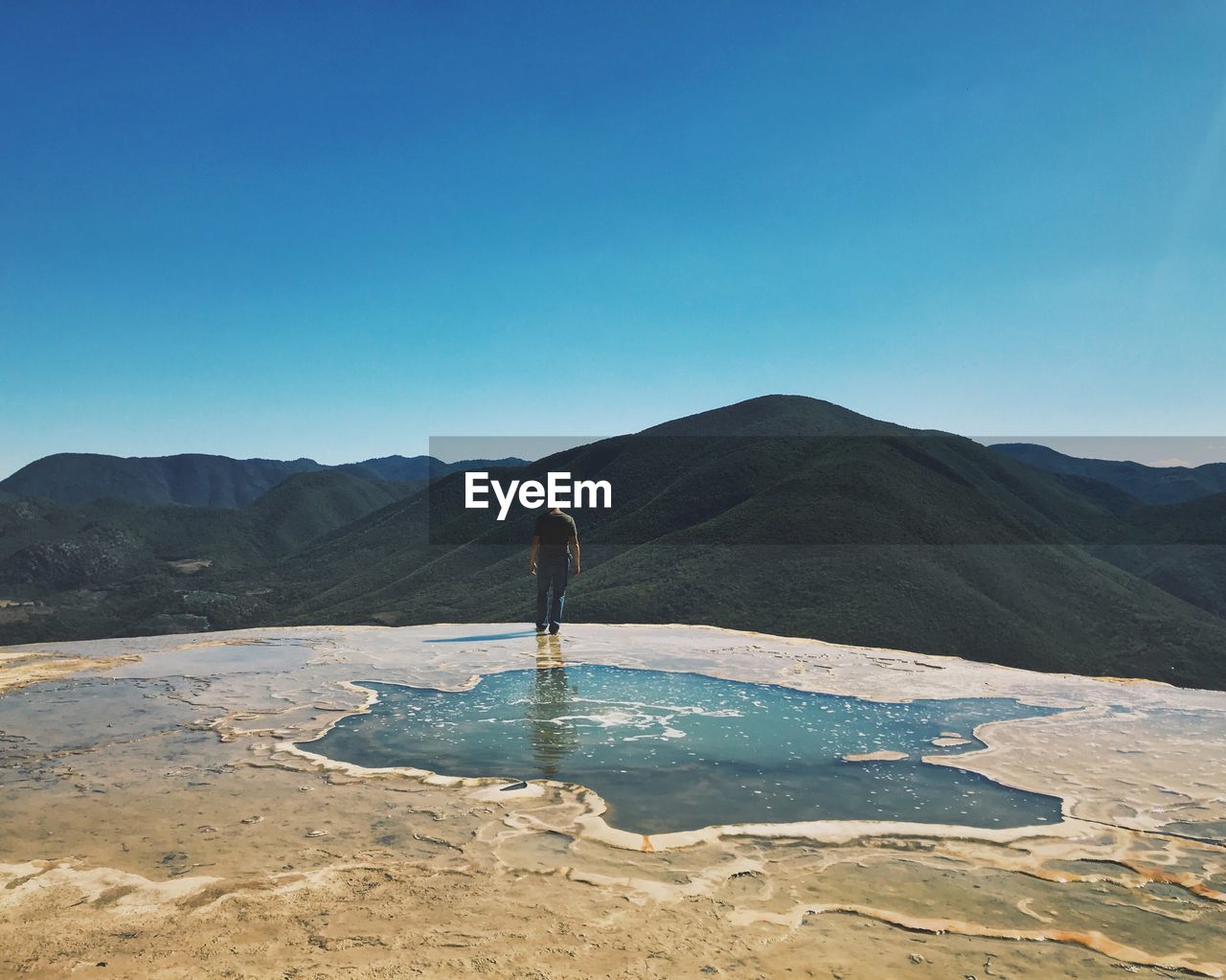 MAN STANDING ON MOUNTAIN AGAINST SKY