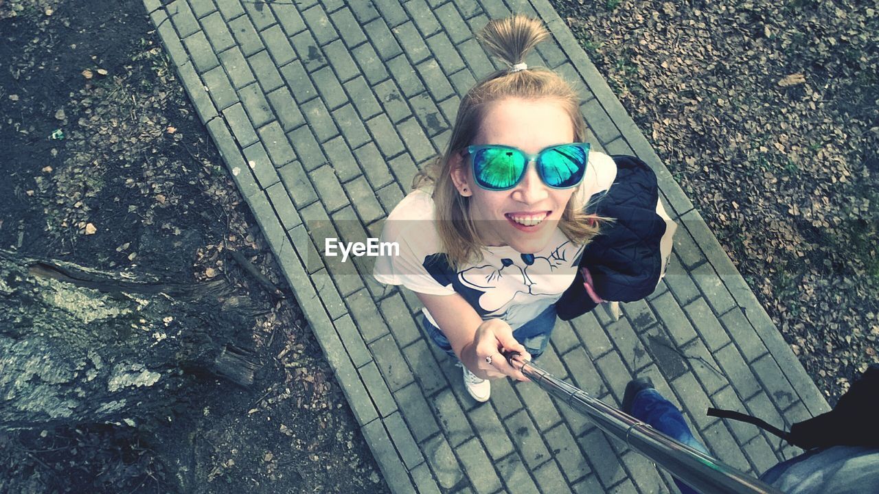 HIGH ANGLE VIEW PORTRAIT OF YOUNG WOMAN SITTING OUTDOORS