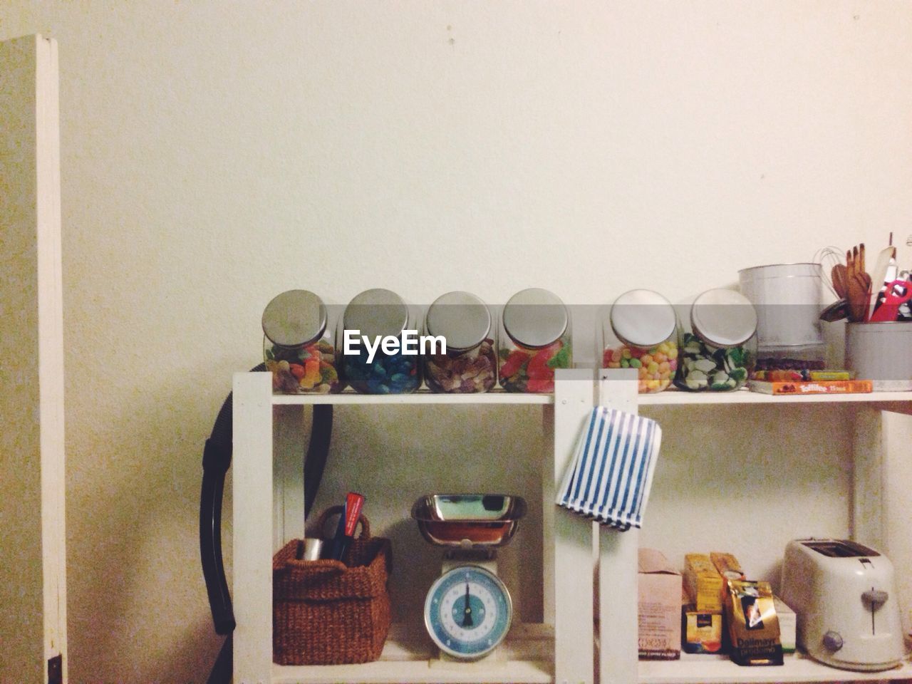 Glass jars with group of objects on shelf against the wall