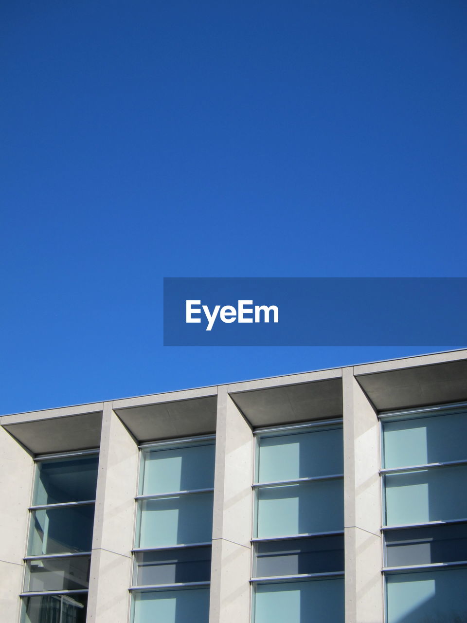 Low angle view of modern building against clear blue sky