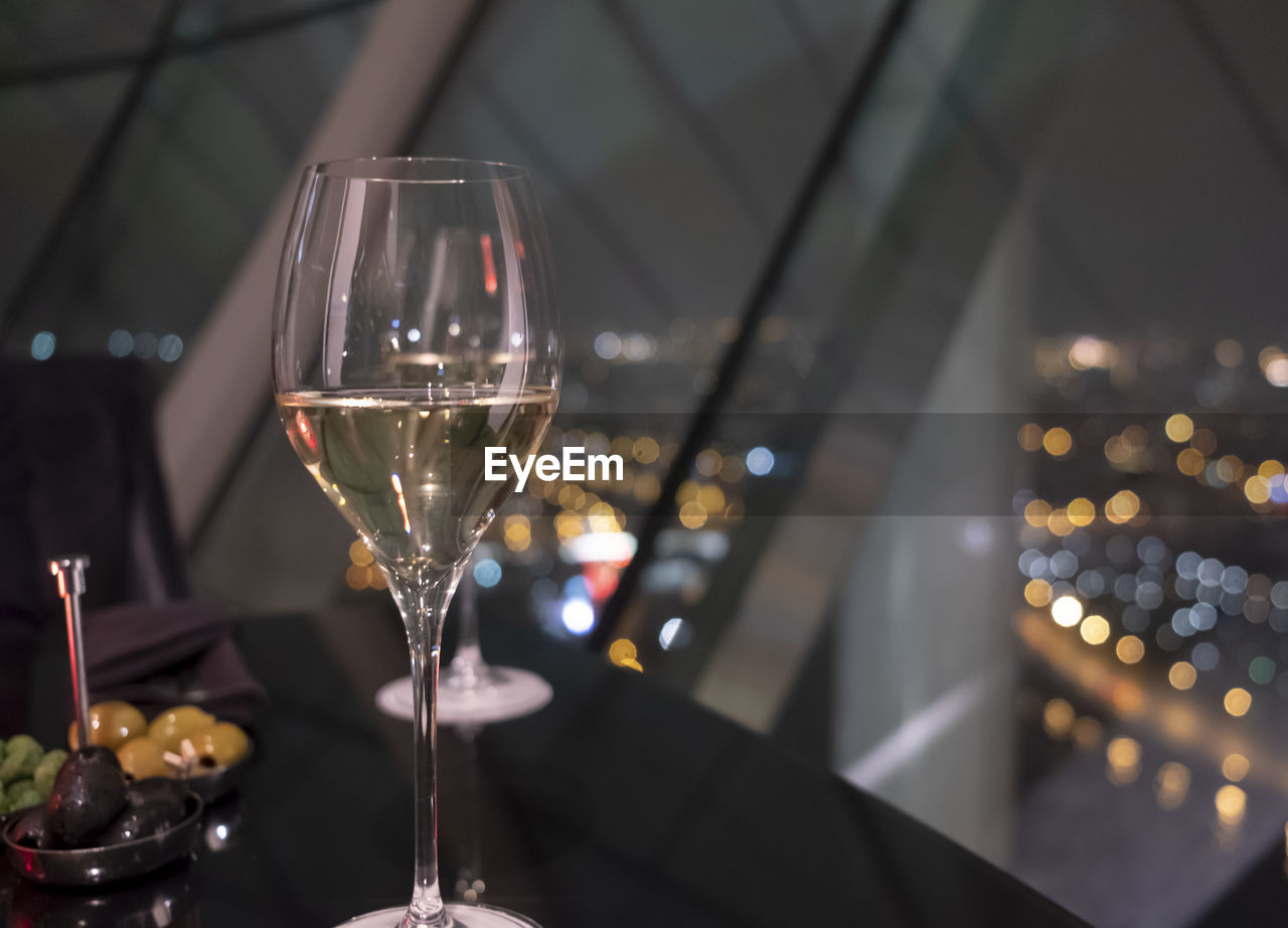 GLASS OF WINE ON TABLE IN ILLUMINATED ROOM