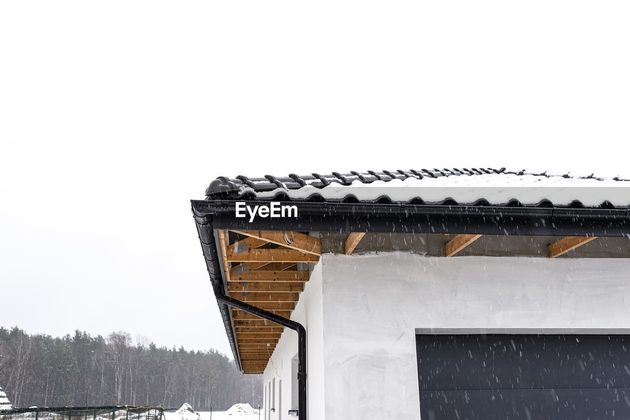 The corner of the roof of a single-family house is covered with snow, the ridge, roof trusses