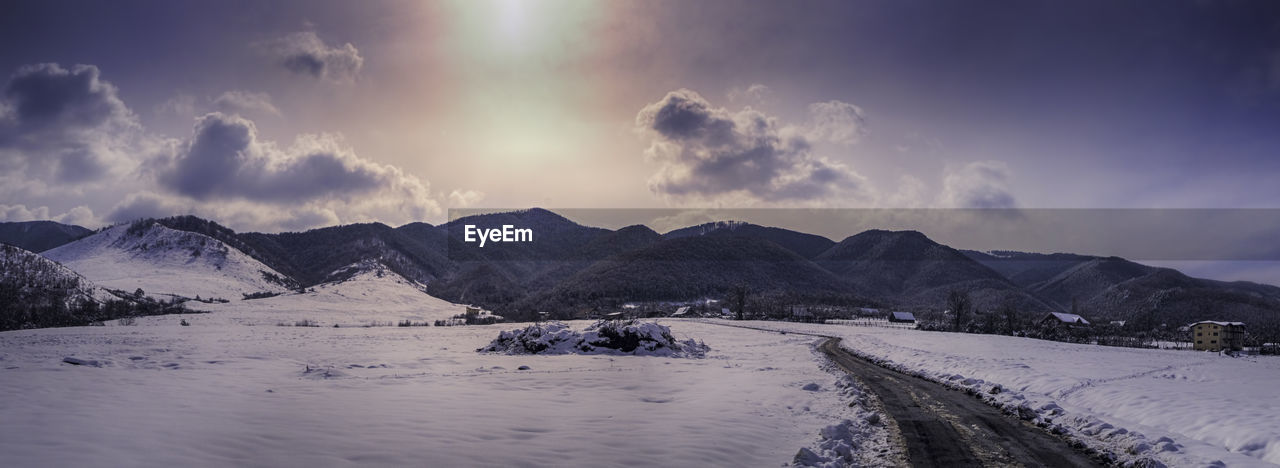 Panoramic view of snow covered mountains against sky