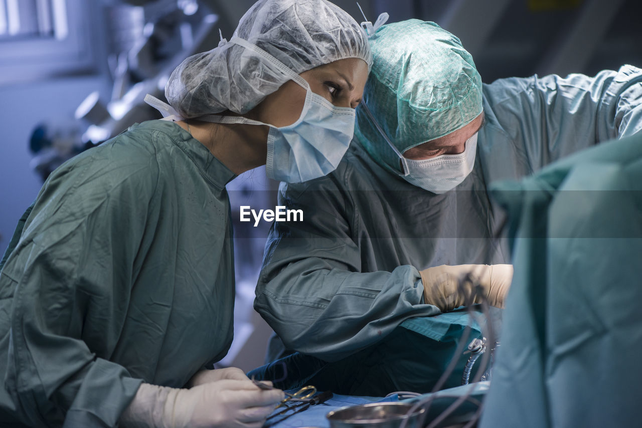 Neurosurgeon with nurse closing operation wound