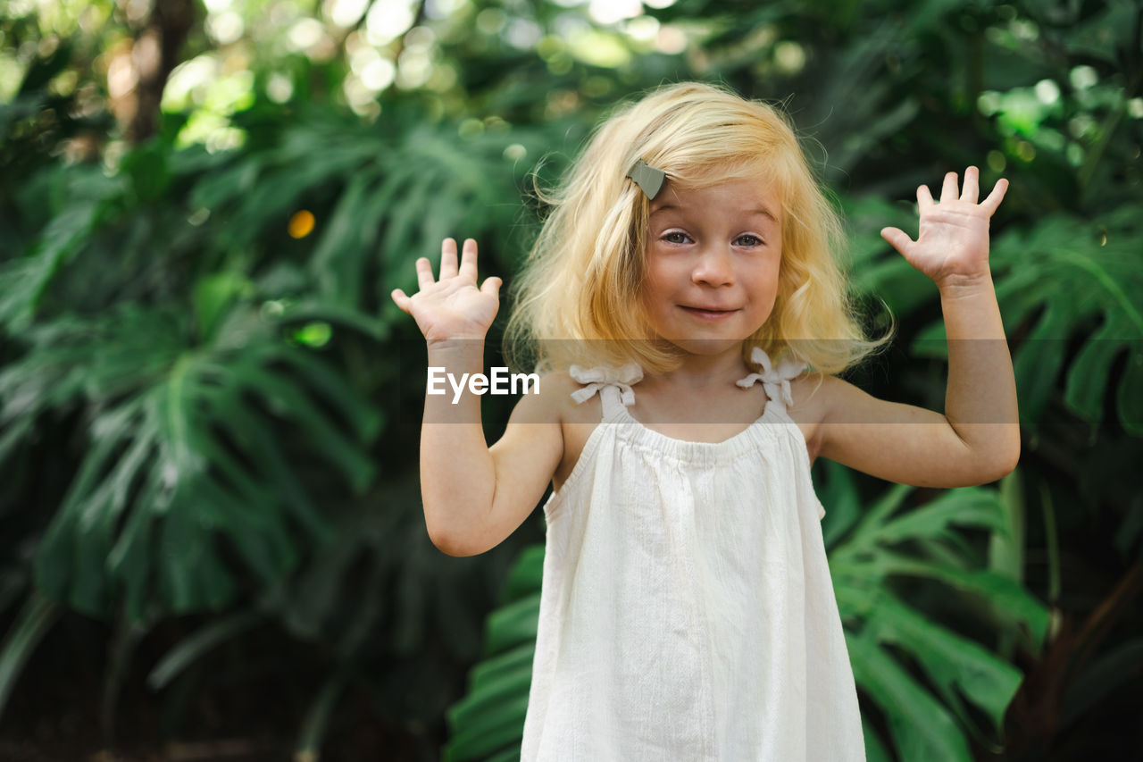 portrait of smiling young woman with eyes closed standing against plants