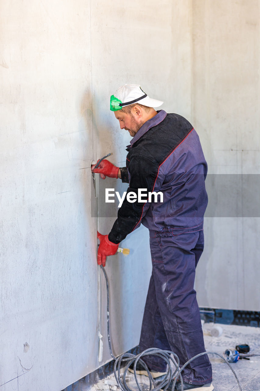 An electrician is laying a cable in an electrical wiring ditch