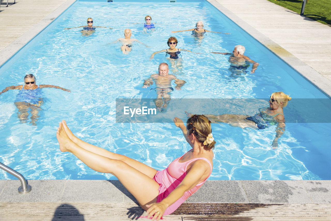 Group of seniors with trainer doing water gymnastics in pool