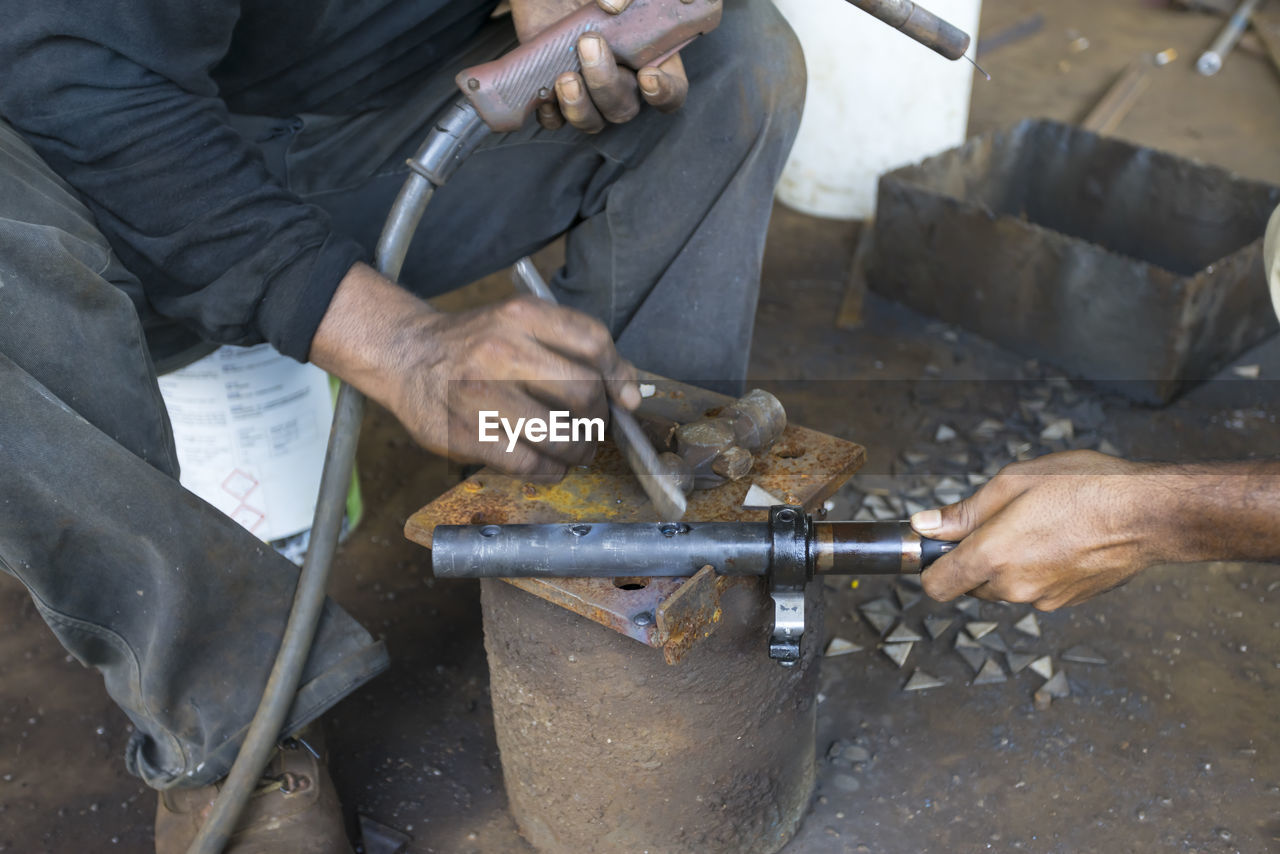 MIDSECTION OF MAN WORKING ON METAL