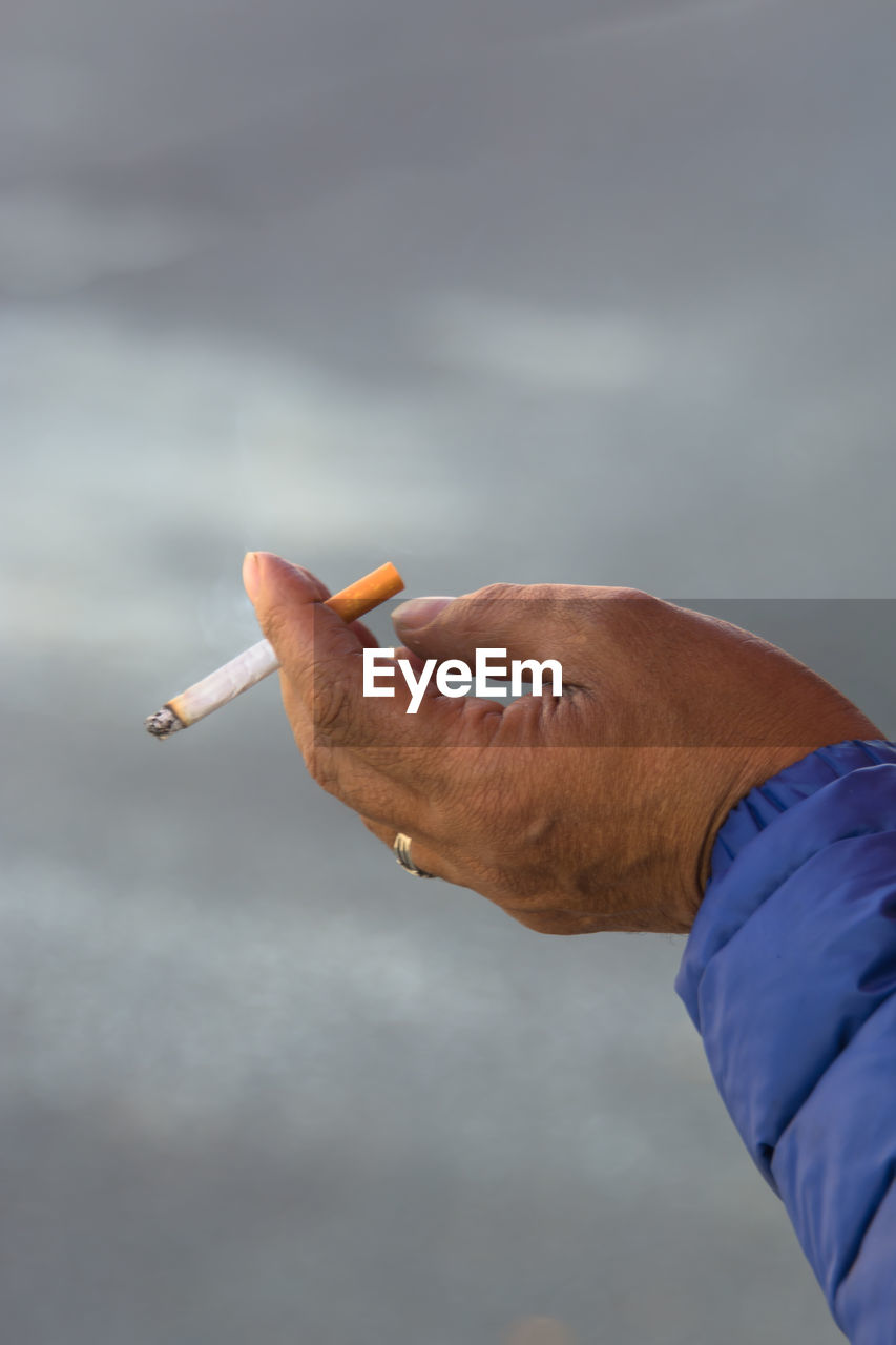 Cropped hand of man smoking cigarette