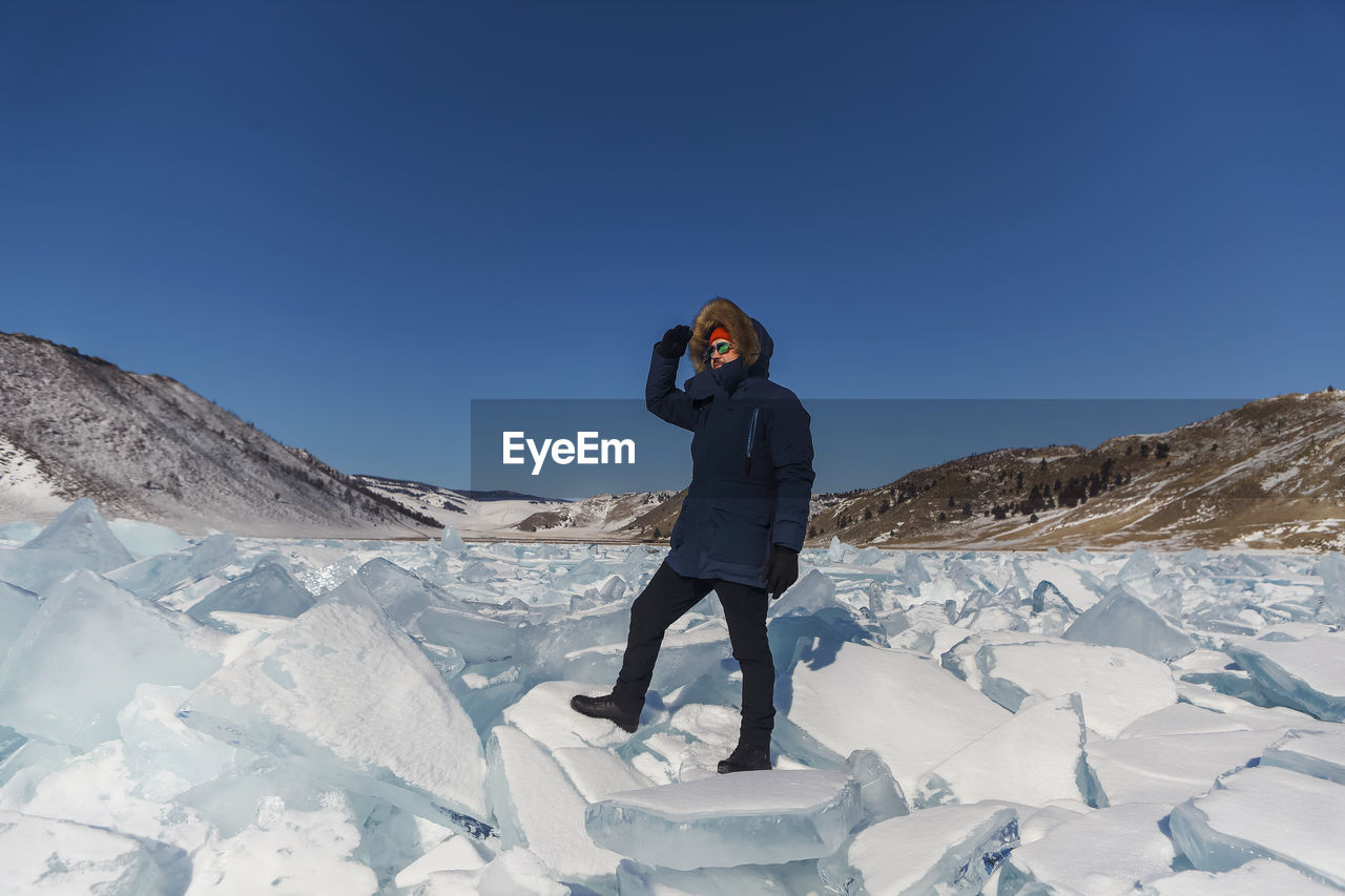 rear view of woman standing on snow covered mountain against clear sky