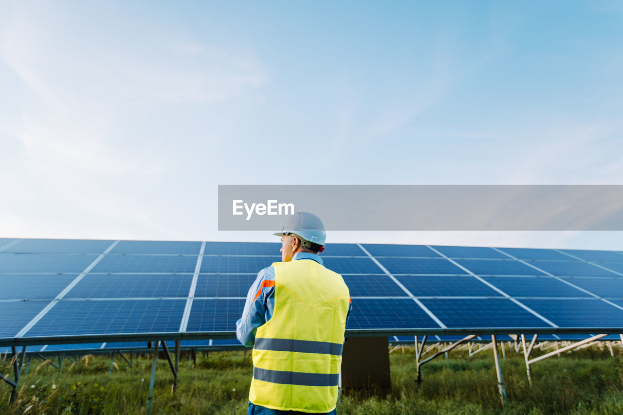 Rear view of worker at solar farm. solar photovoltaic panels. eco alternative energy concept