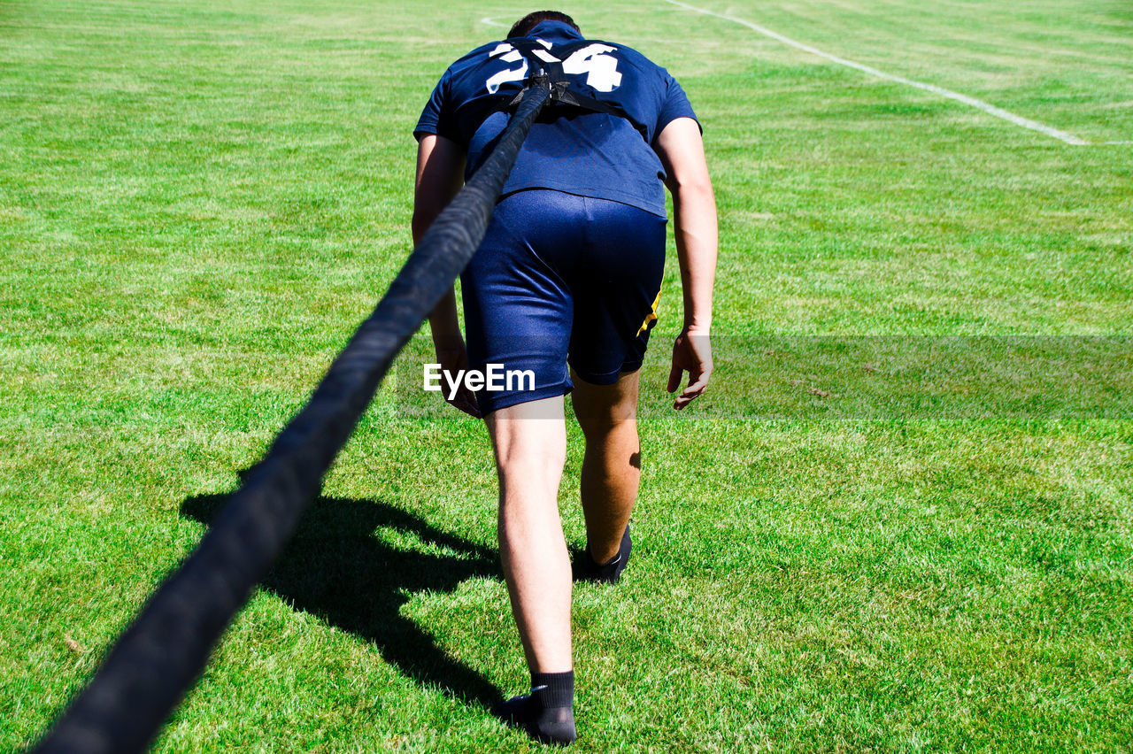 Rear view of man exercising on grassy field