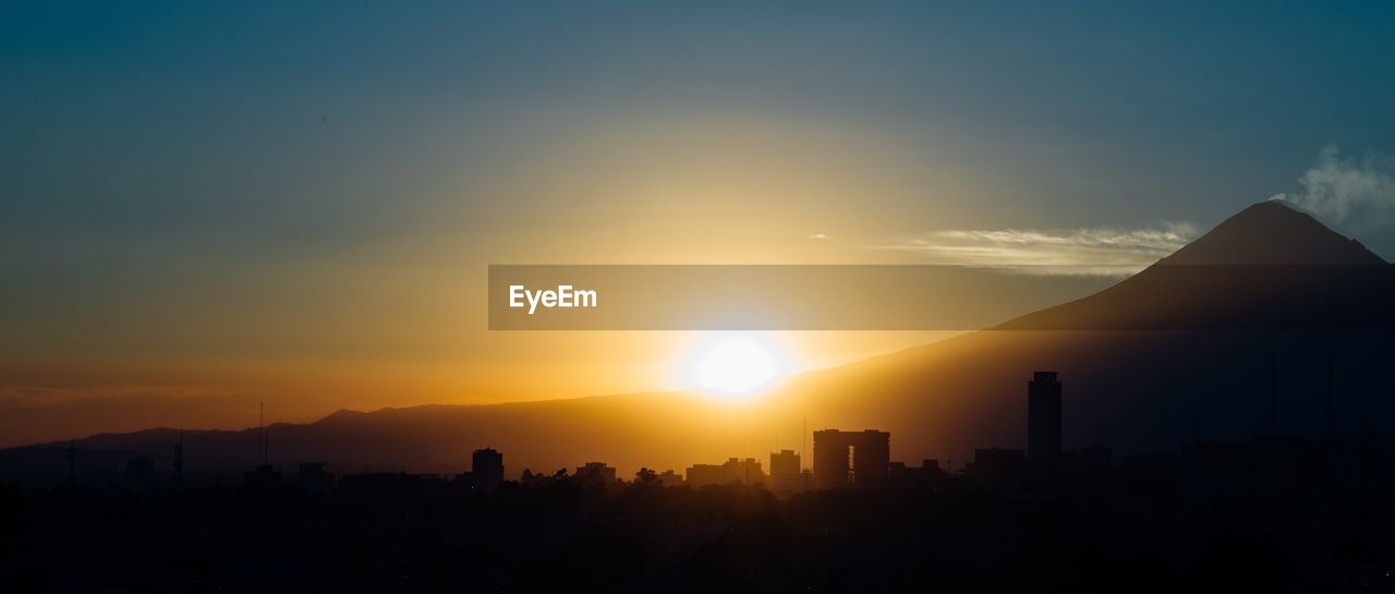 SILHOUETTE BUILDINGS AGAINST SKY AT SUNSET