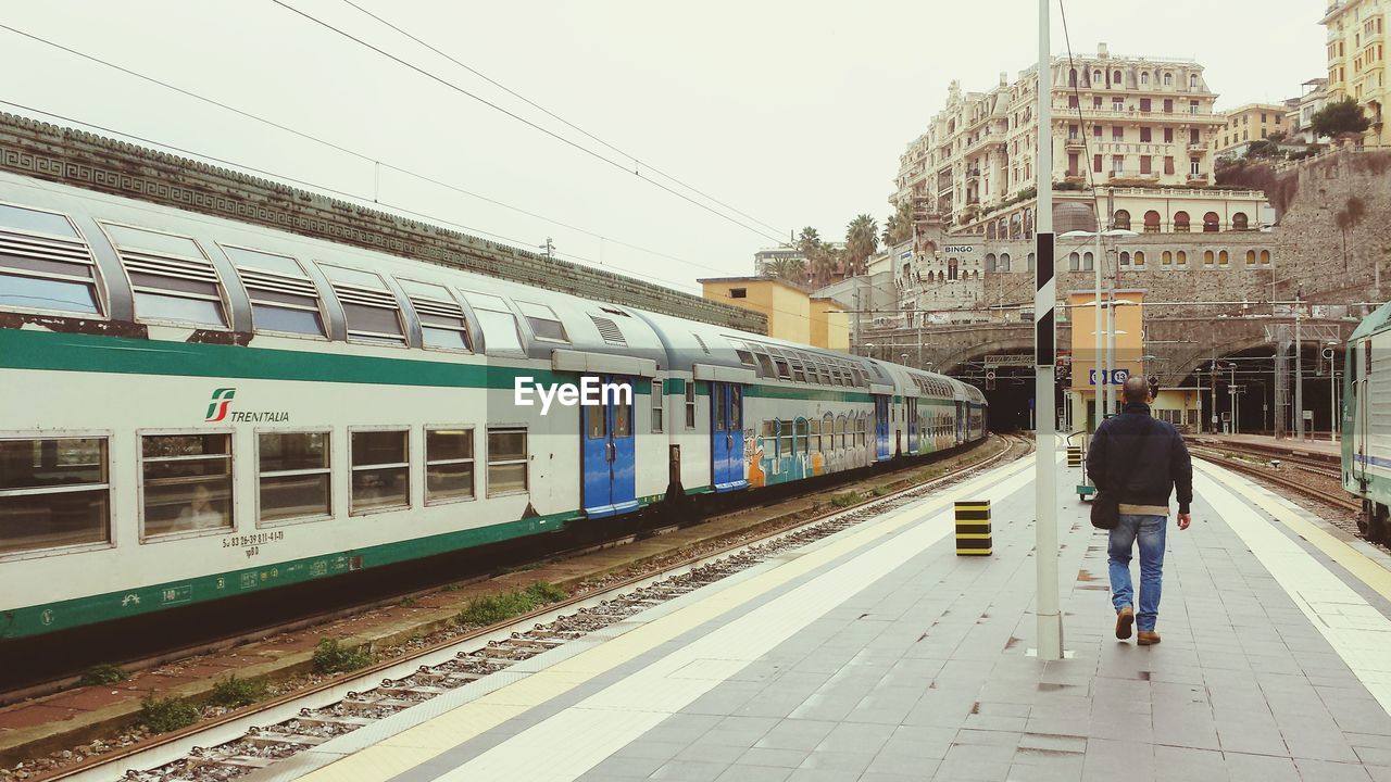 MAN AND WOMAN AT RAILROAD STATION IN CITY