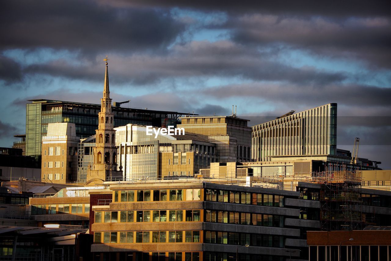 Buildings in city against cloudy sky