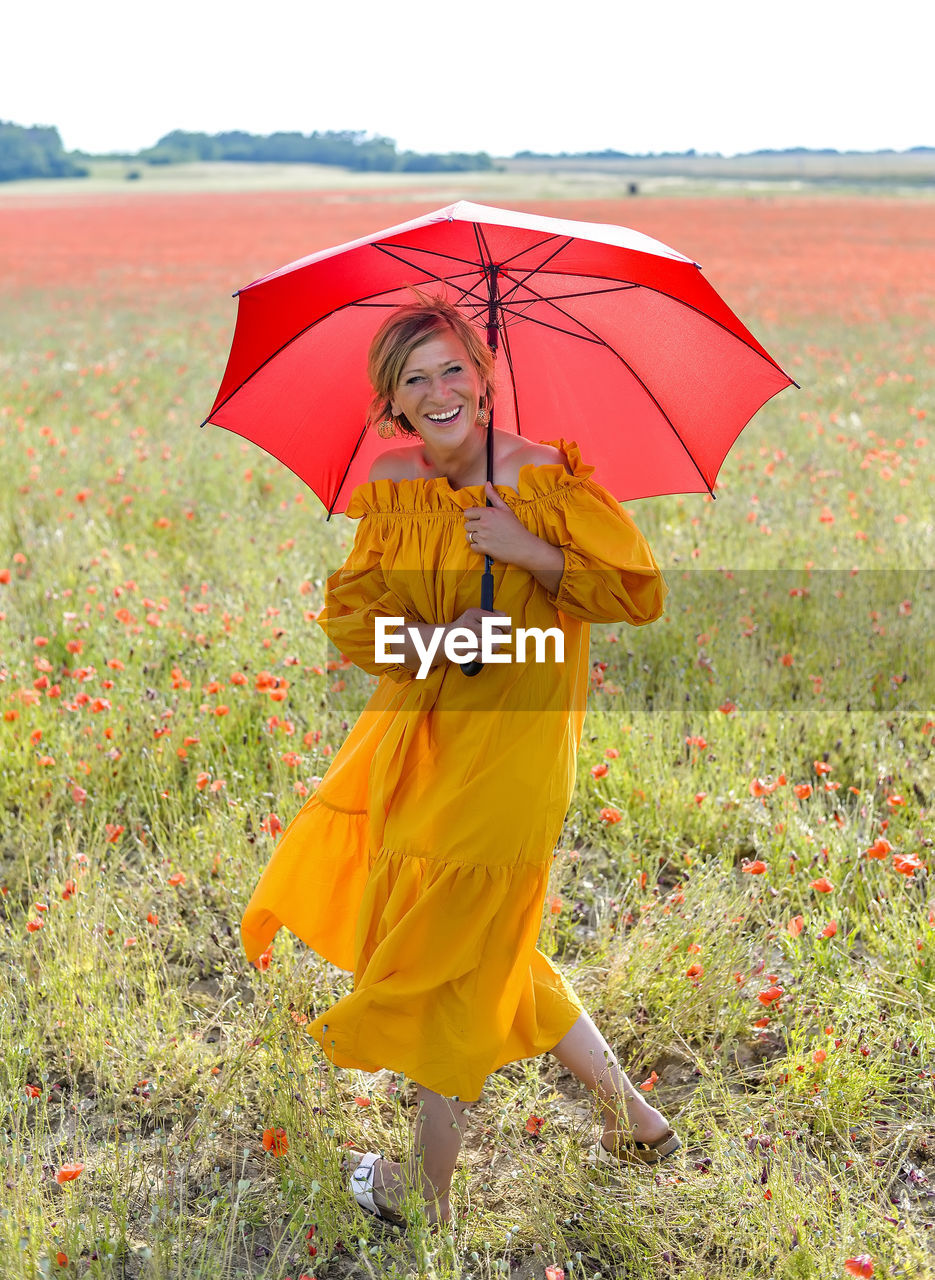 Happy woman with umbrella walking on grassy land