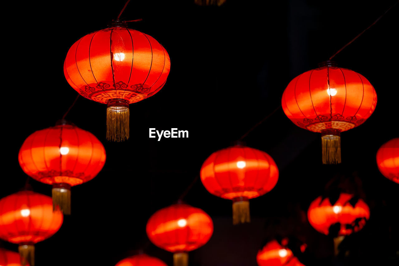 LOW ANGLE VIEW OF ILLUMINATED LANTERNS HANGING IN NIGHT