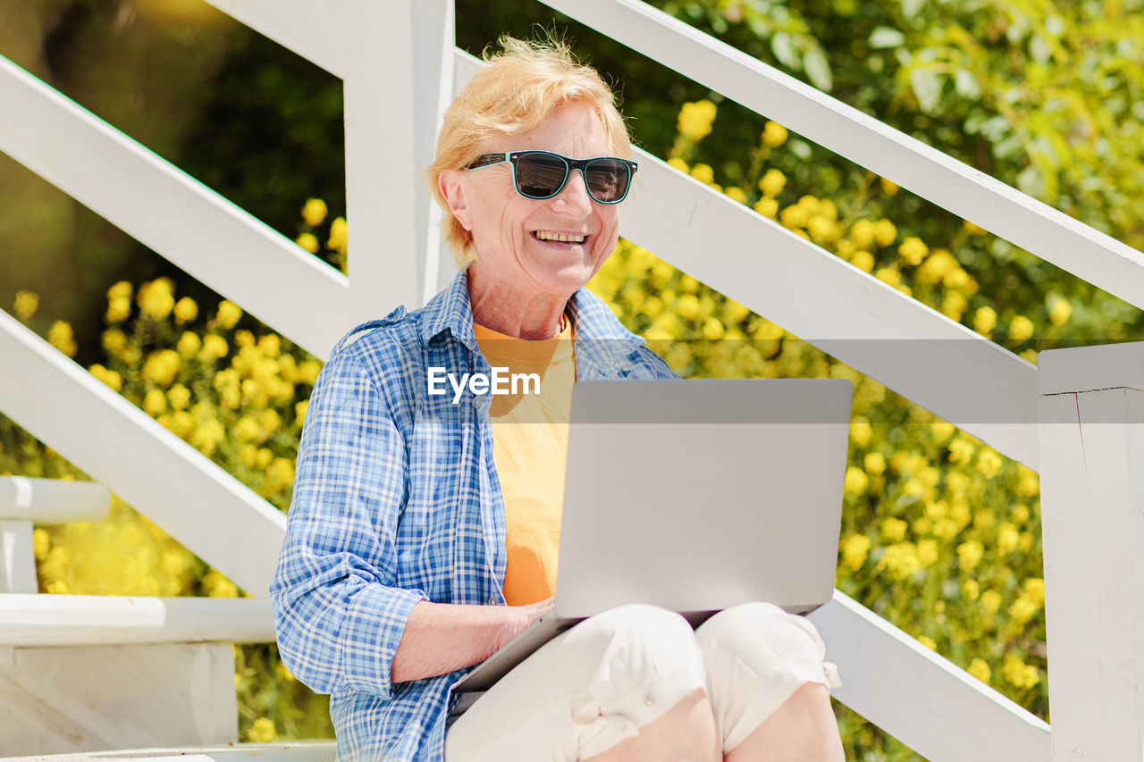 Senior authentic woman using laptop for distance learning education outdoors