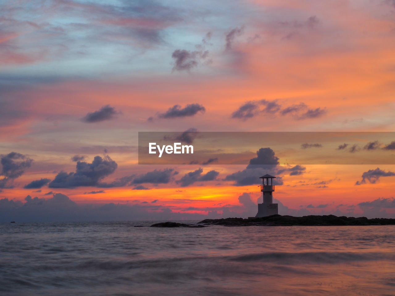 LIGHTHOUSE ON SEA AGAINST SKY DURING SUNSET