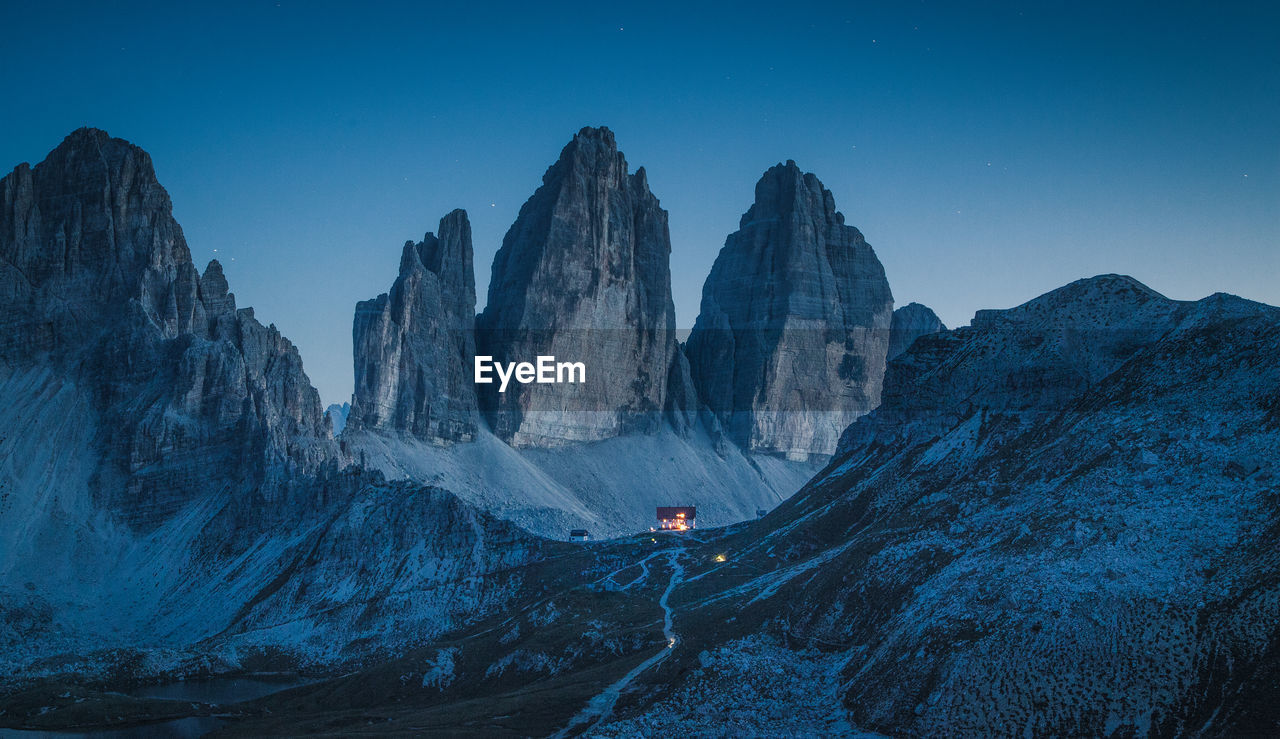 Panoramic view of rocky mountains against blue sky