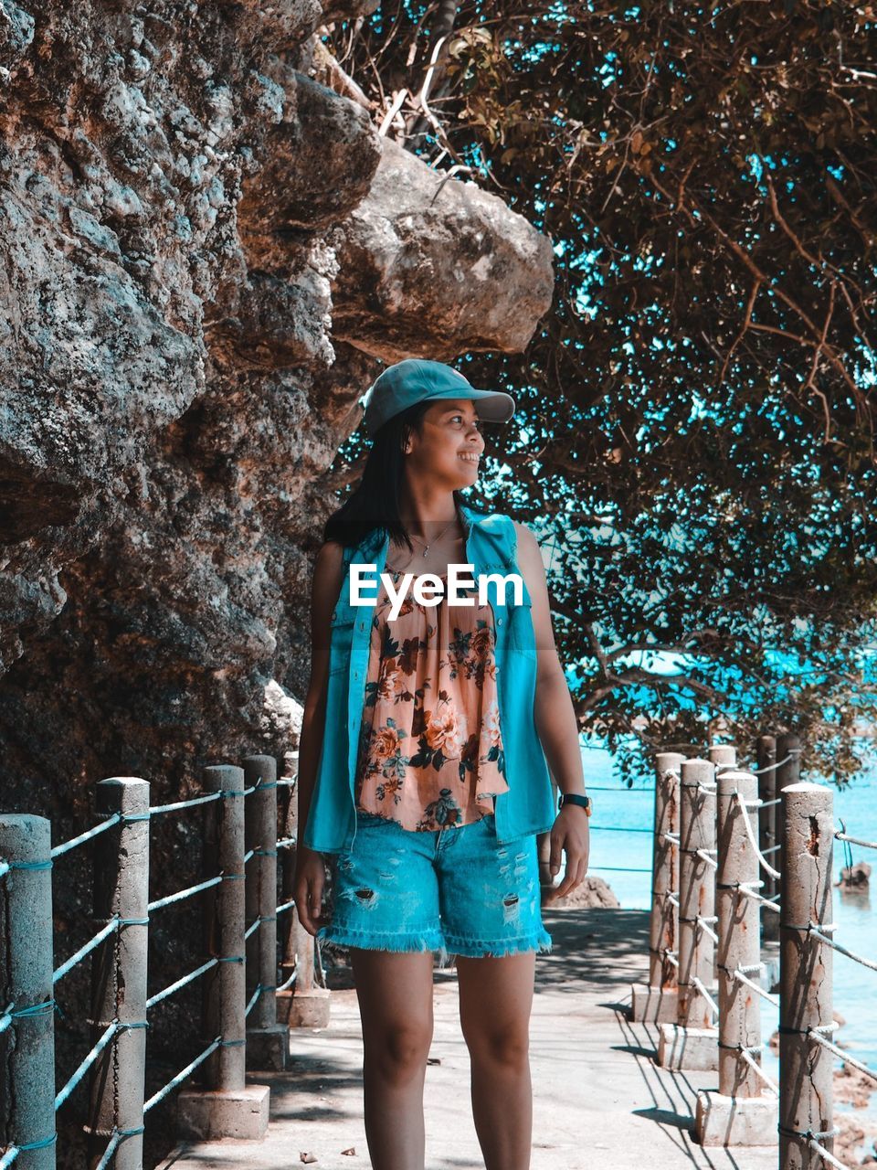 Woman walking on footbridge against tree