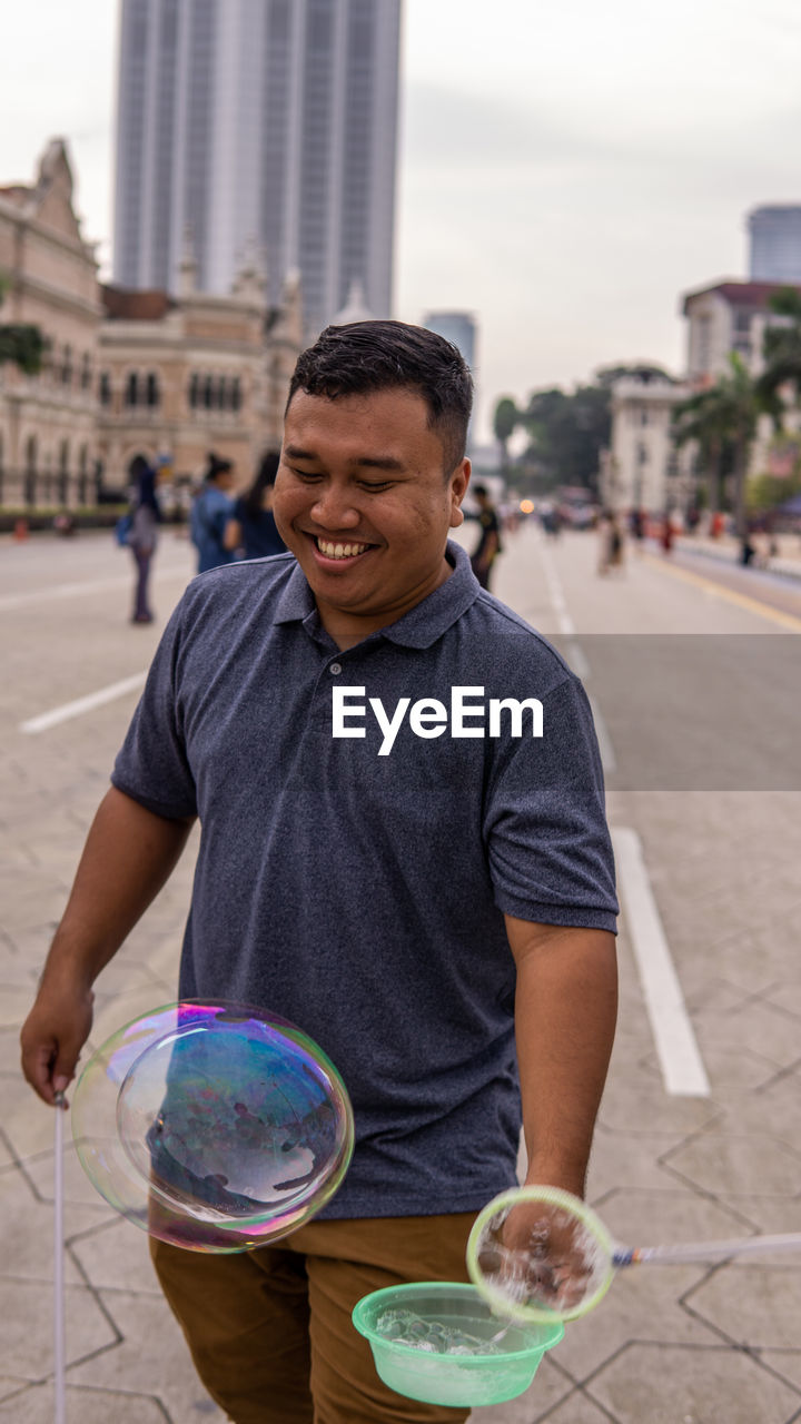 MAN HOLDING CAMERA IN CITY