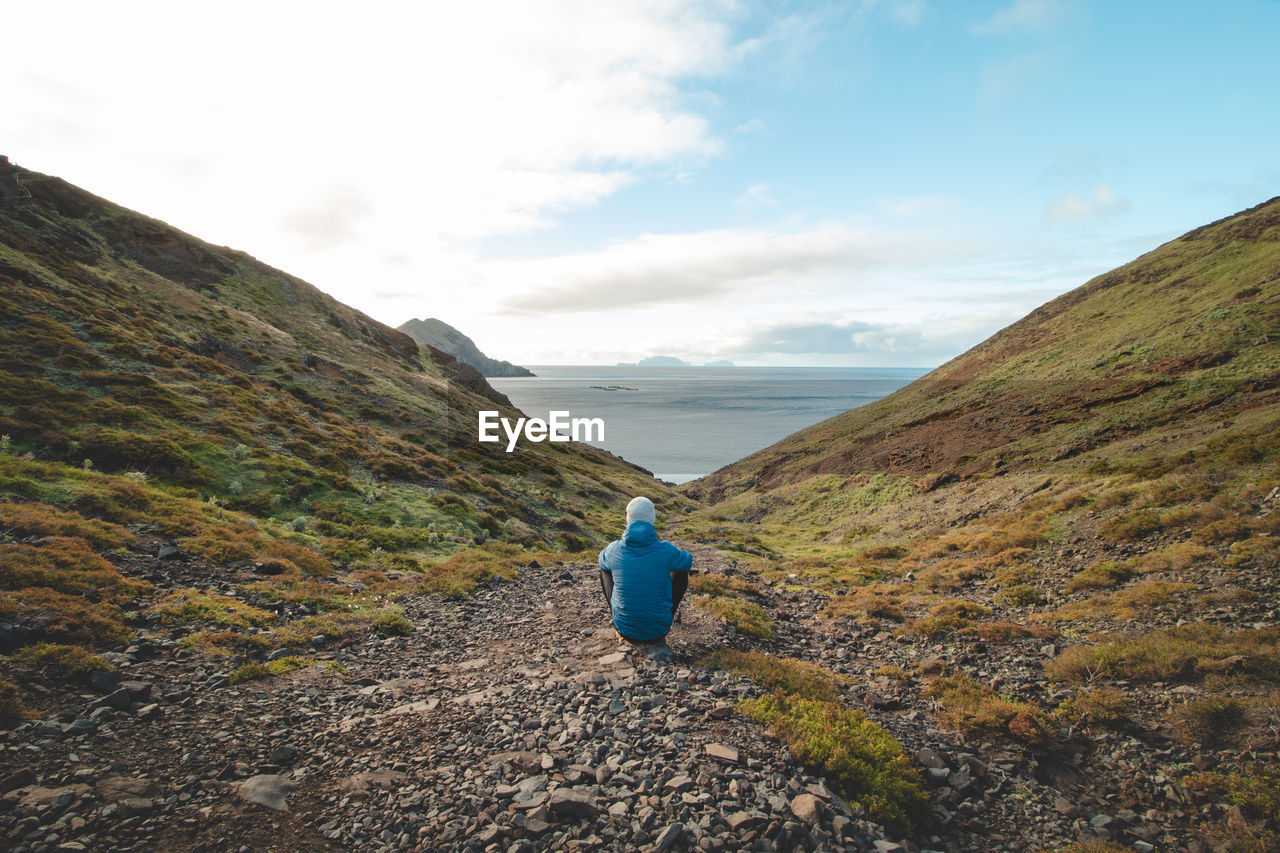 rear view of woman walking on mountain against sky