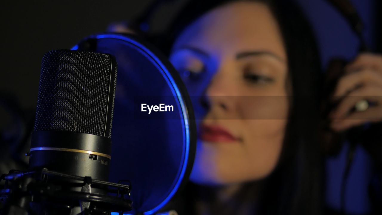 Close-up of woman singing by microphone in studio