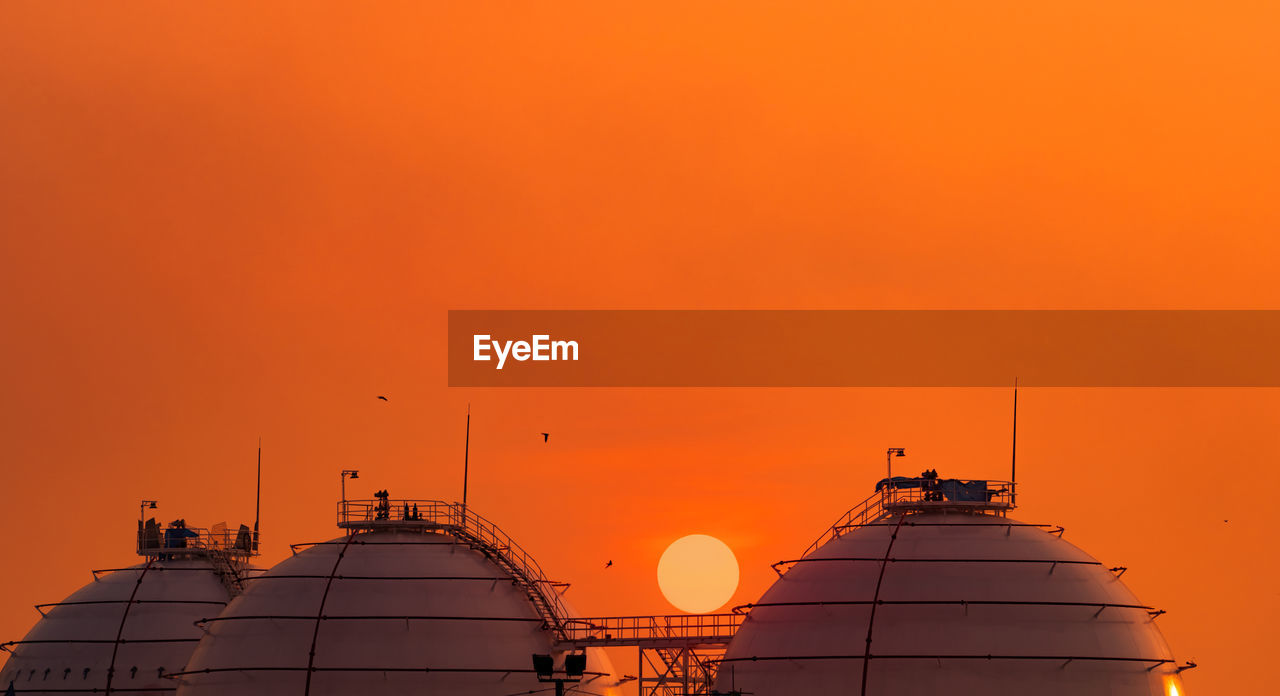 Industrial gas storage tank on orange sunset sky. lng or liquefied natural gas storage tank. 