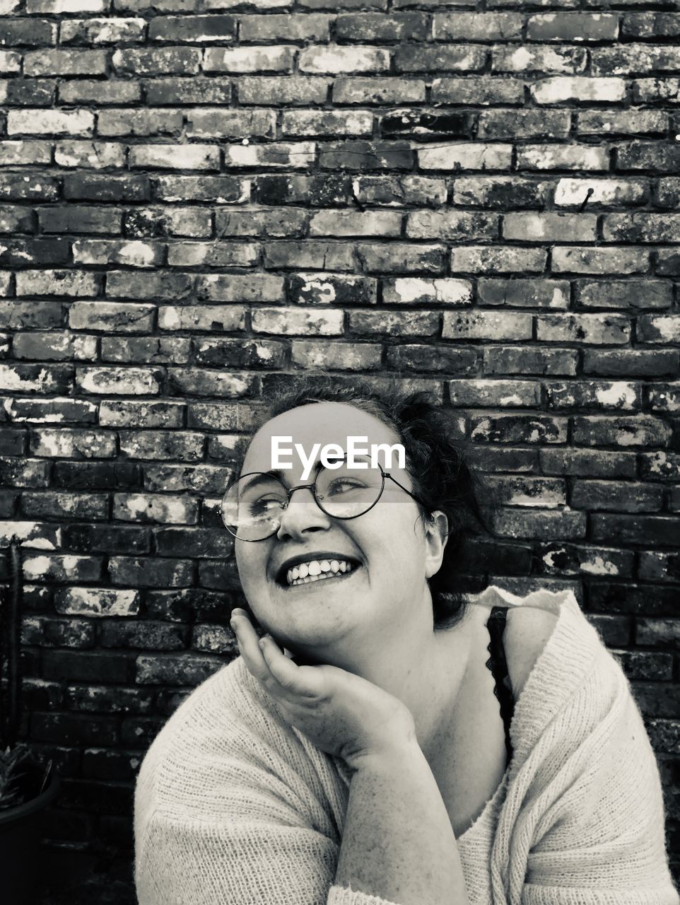 Portrait of smiling young man against brick wall