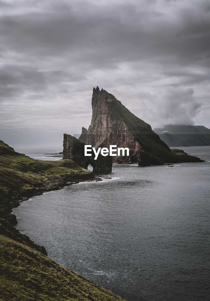 Scenic view of seascape by mountains against sky