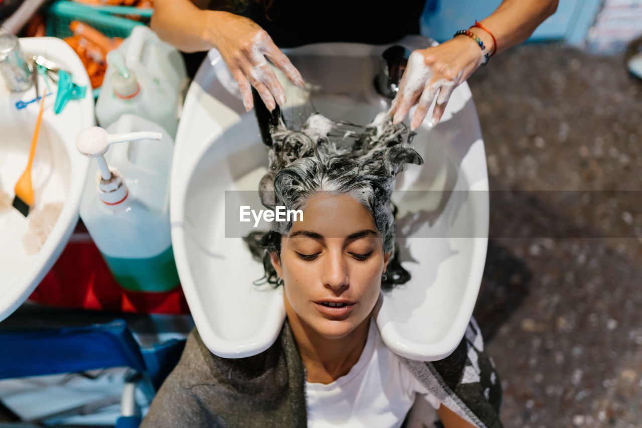 Woman in the hairdresser's shop shampooing her hair