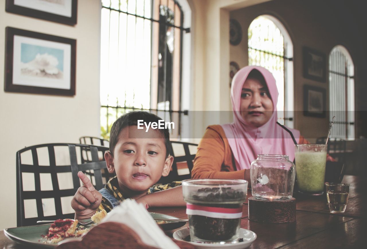 Boy and woman having food on table