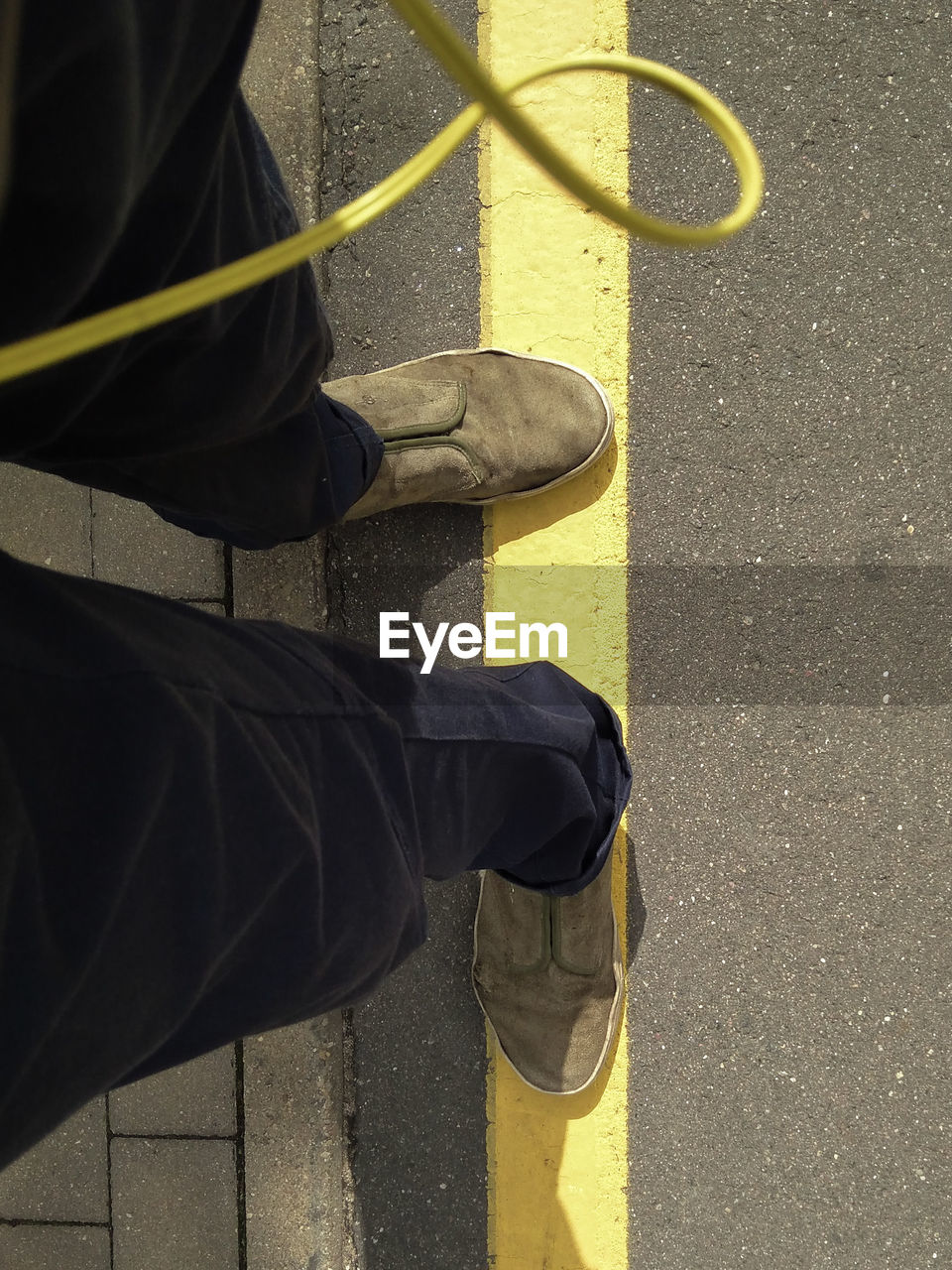 LOW SECTION OF MAN STANDING ON YELLOW STREET