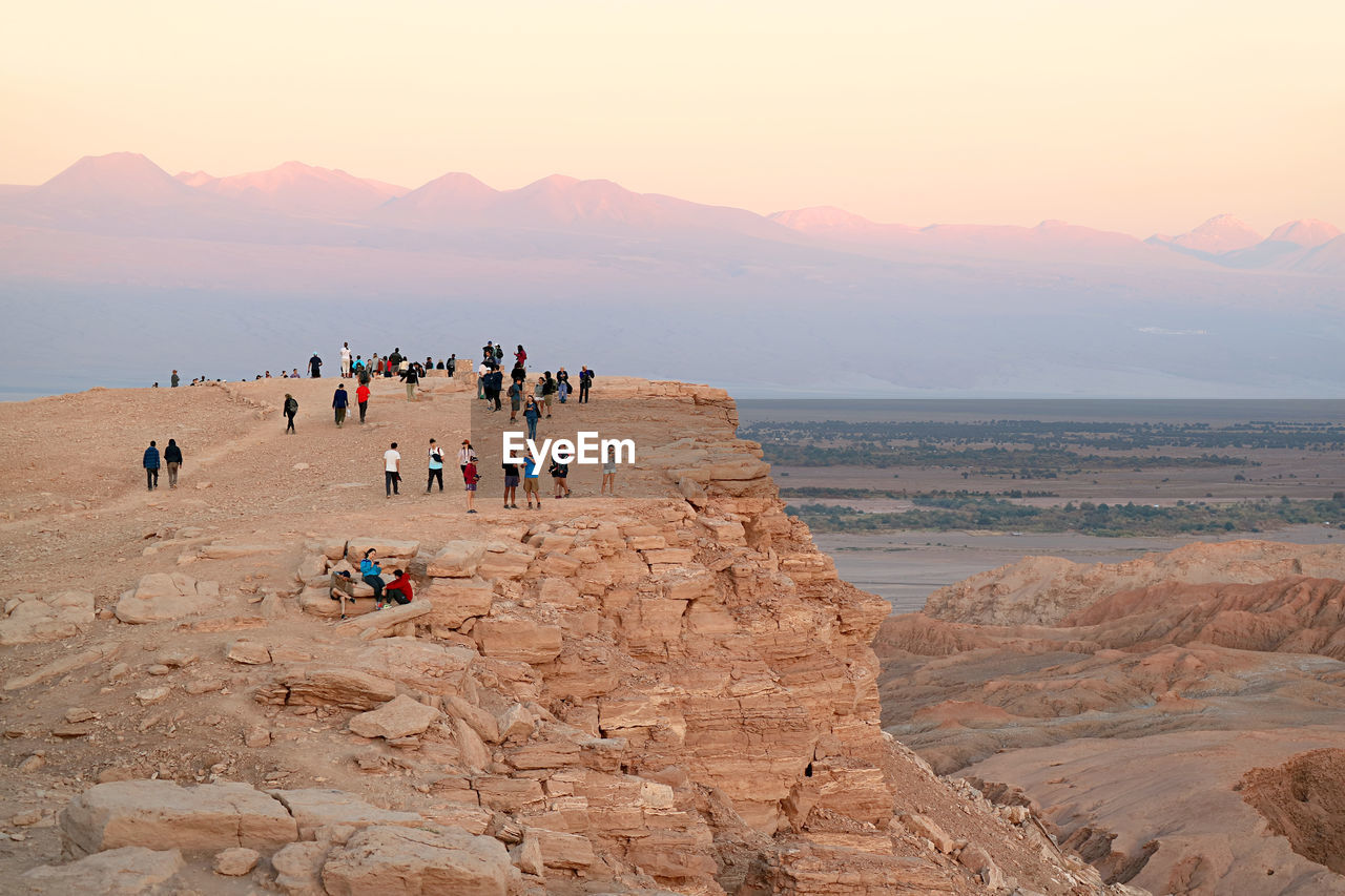 Visitors on the cliff waiting for sunset at valle de la luna or moon valley in atacama desert, chile