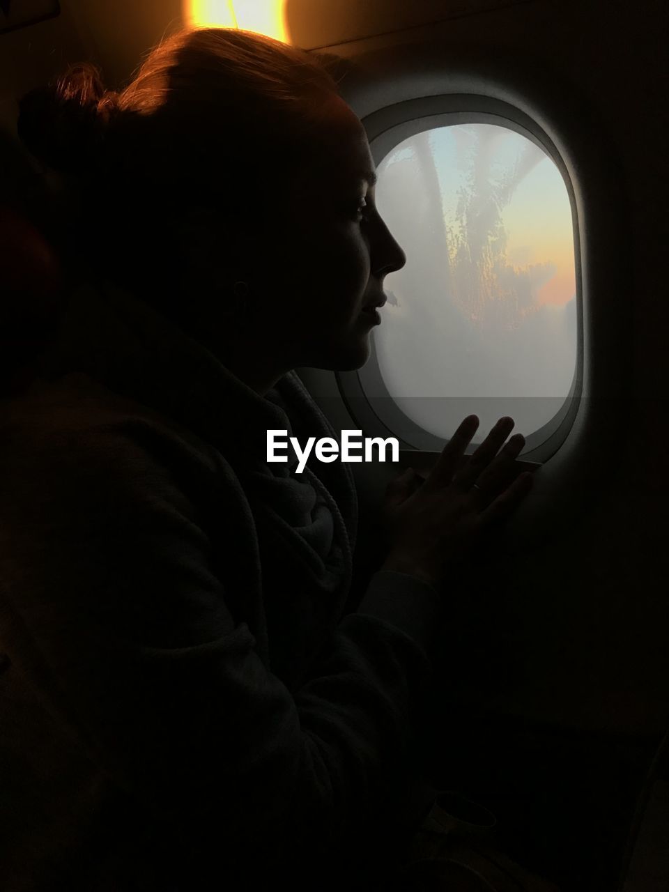 Rear view of woman looking through window in airplane 