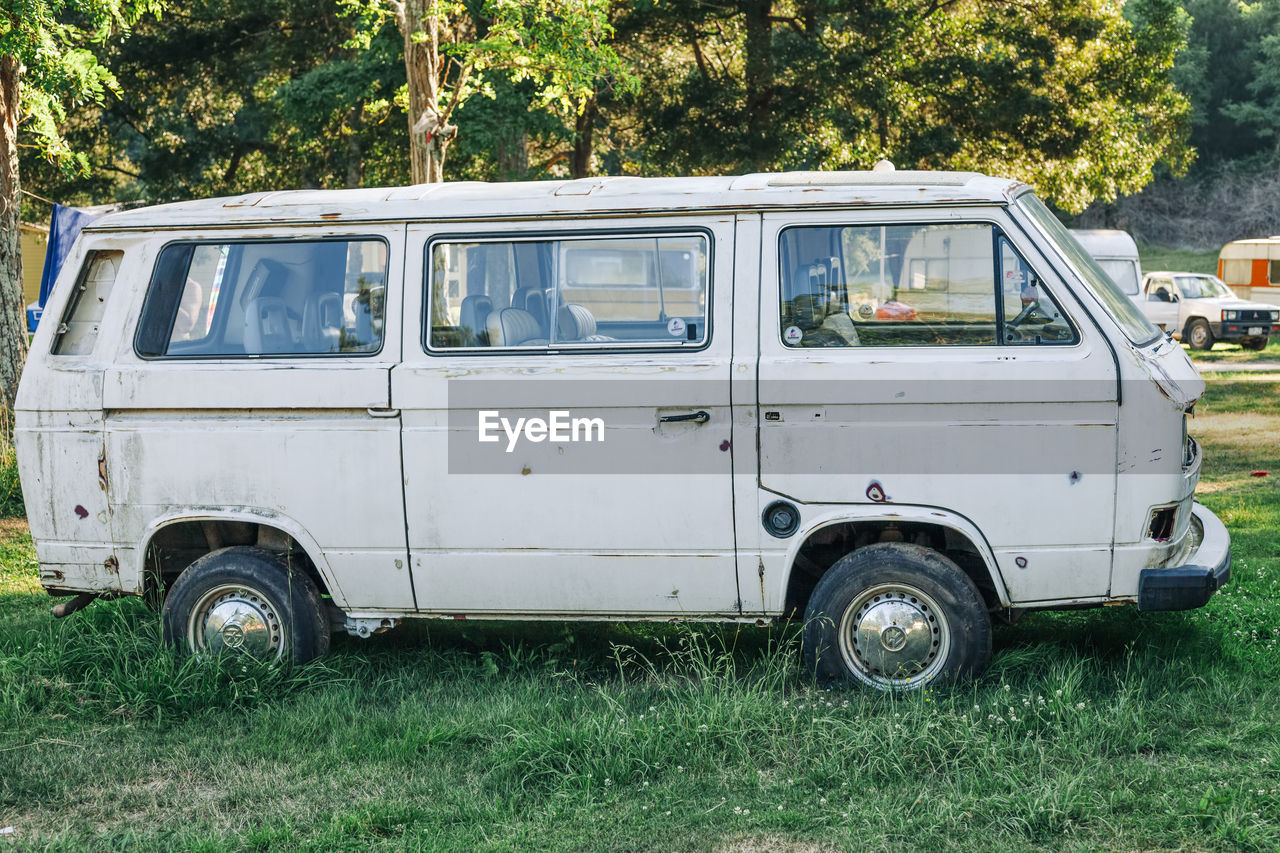 VINTAGE CAR ON FIELD BY TREES