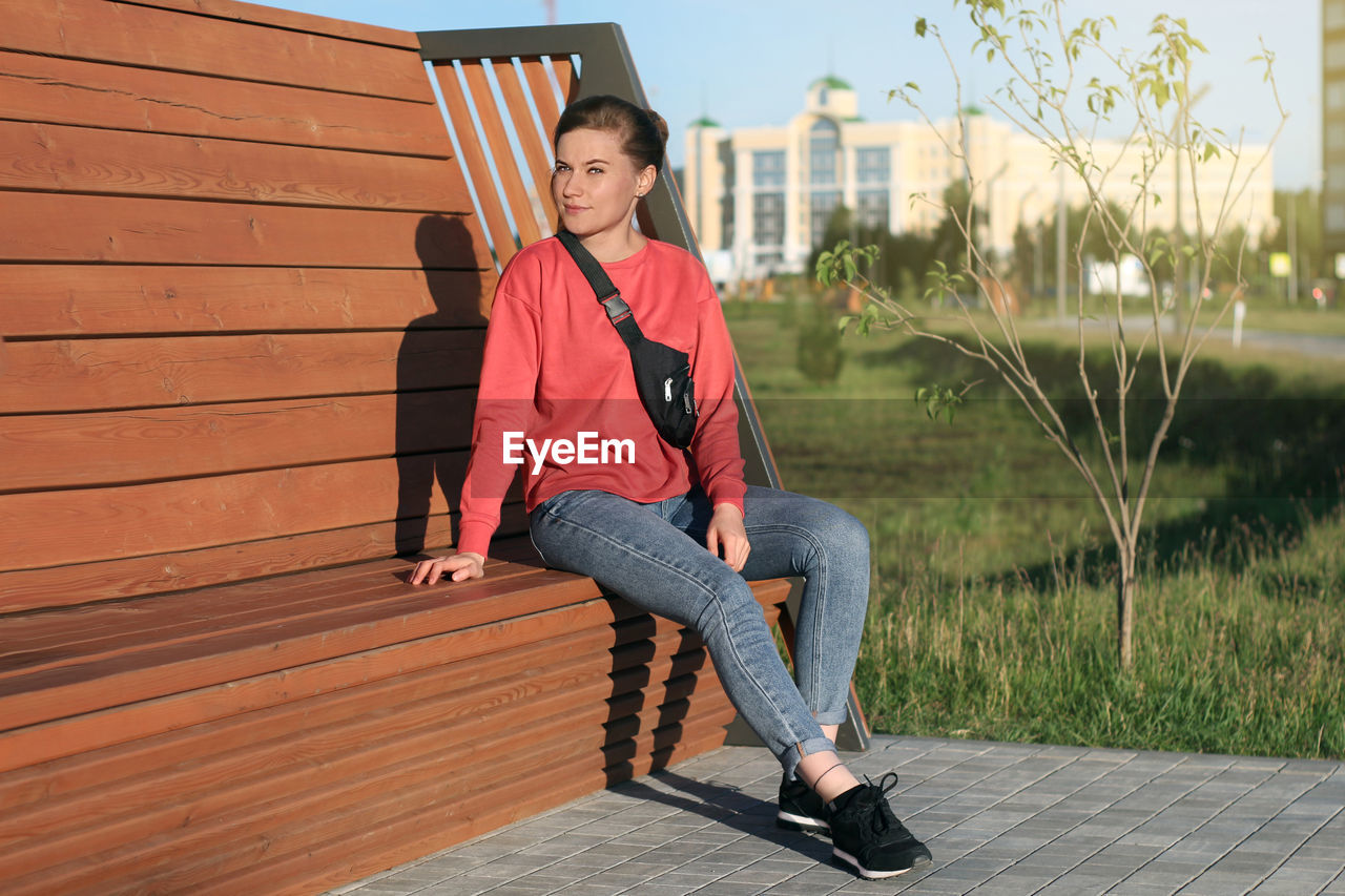 Girl sitting on a bench on a city street