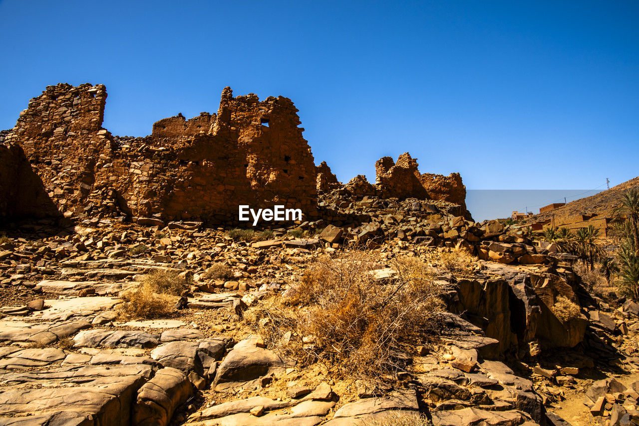 rock, sky, rock formation, landscape, nature, scenics - nature, travel destinations, environment, land, travel, valley, beauty in nature, clear sky, natural environment, wadi, no people, non-urban scene, desert, blue, mountain, geology, arch, formation, sunny, wilderness, outdoors, tranquility, semi-arid, sunlight, ancient history, terrain, tourism, extreme terrain, plateau, climate, tranquil scene, architecture, eroded, sandstone, cliff, physical geography, plant, remote